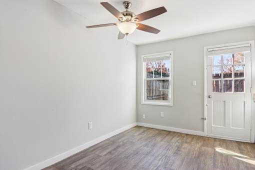 A room with a ceiling fan and a door.