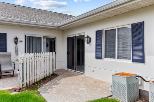 a white house with a white picket fence and a backdoor to a patio