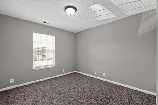 A room with a window and a carpeted floor.