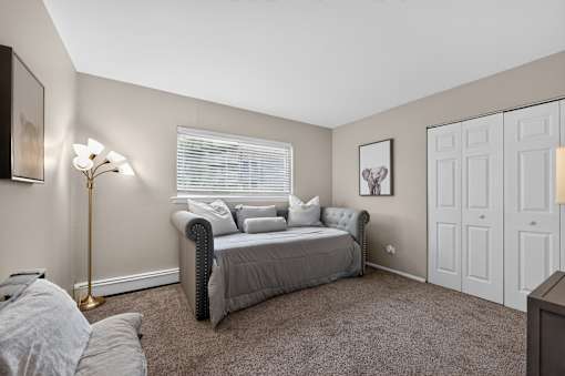 Bedroom at Renaissance at Carol Stream featuring a bed, lamp, and wall art in Carol Stream, IL.