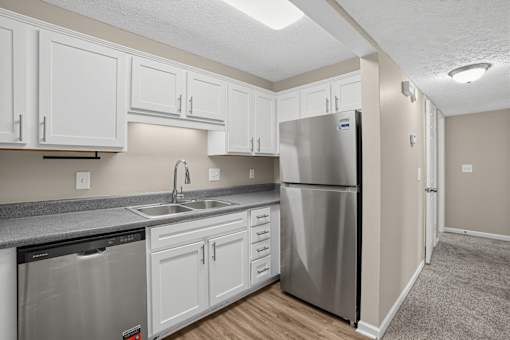 Apartment kitchen with a stainless steel refrigerator and white cabinets at Arbours at Victoria Place in Prattville, AL