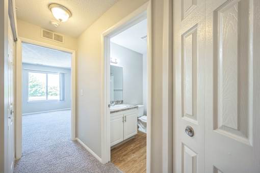 A white door is open to a kitchen and living room.