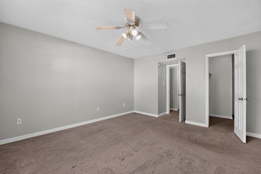 Empty room with a ceiling fan and carpeted floor.