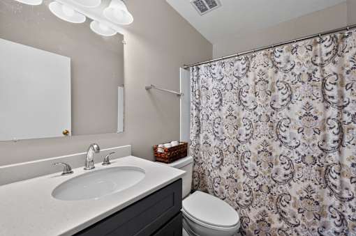 Bathroom at Renaissance at Carol Stream featuring a floral shower curtain and white toilet in Carol Stream, IL.