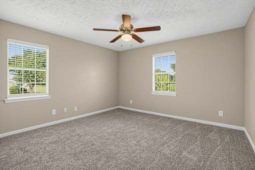 Room with a ceiling fan and two windows at Arbours at Victoria Place in Prattville, AL