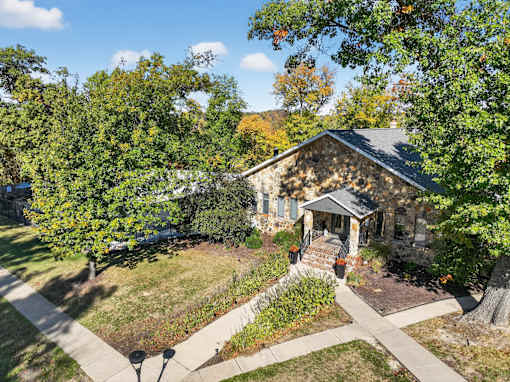 A small house with a porch is surrounded by trees.