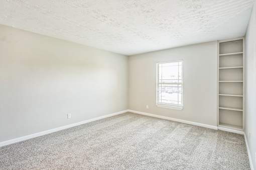 A room with a carpeted floor and a window.