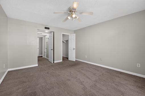 A room with a ceiling fan and carpeted floor.