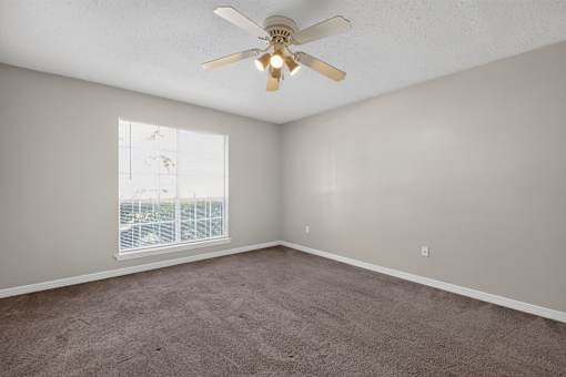 A room with a ceiling fan and a window.
