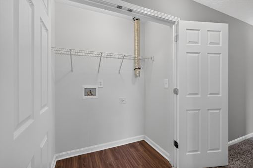 A white closet with a wooden floor and a white door.
