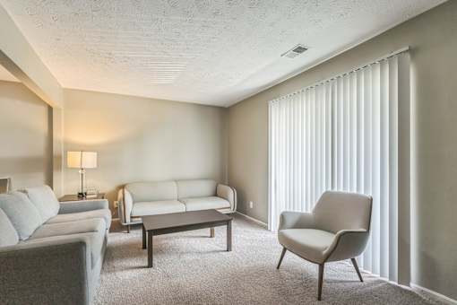 A living room with a grey couch, a white chair, and a grey armchair.