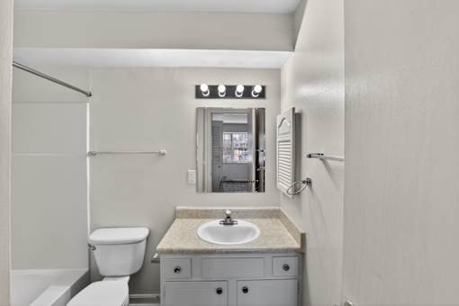 A bathroom with a toilet, sink, and mirror.