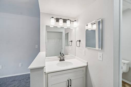 A bathroom with a sink, mirror, and lighting fixture.