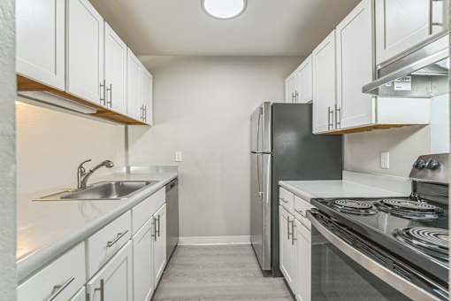 A kitchen with white cabinets and a black refrigerator.