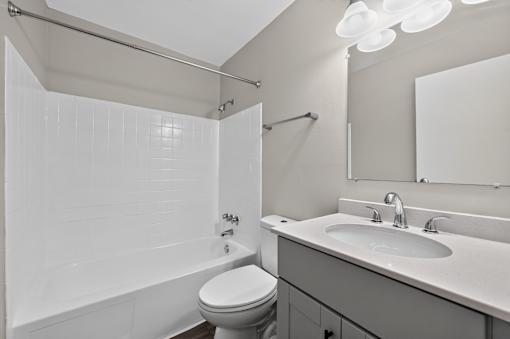 White bathroom at Renaissance at Carol Stream featuring a toilet, sink, and shower in Carol Stream, IL.