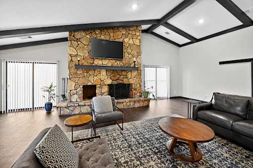A living room with a stone fireplace and a flat screen TV mounted above it.