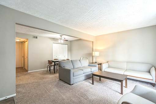 A living room with a grey couch, a white couch, and a brown coffee table.