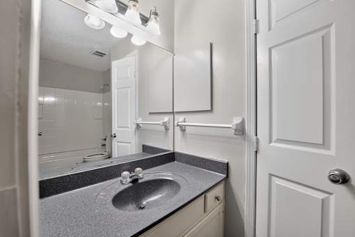 A bathroom with a sink, mirror, and lighting fixture.