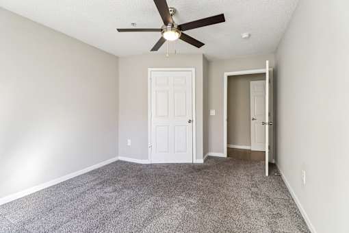 A room with a ceiling fan and carpeted floor.