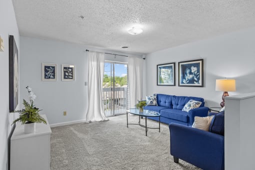 a living room with blue couches and a glass coffee table