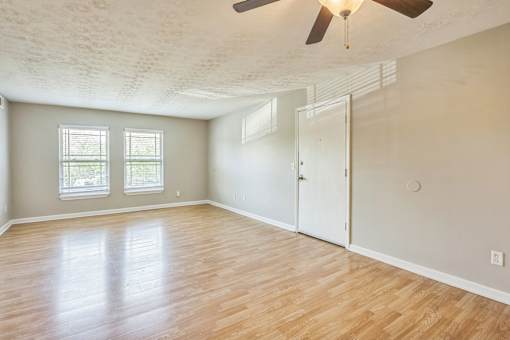 A room with a ceiling fan and wooden flooring.