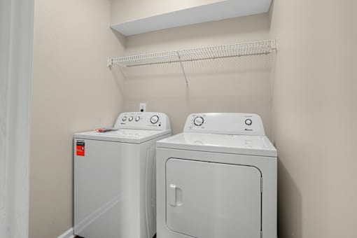 Two white front-loading washing machines in a laundry room at Arbours at Victoria Place in Prattville, AL