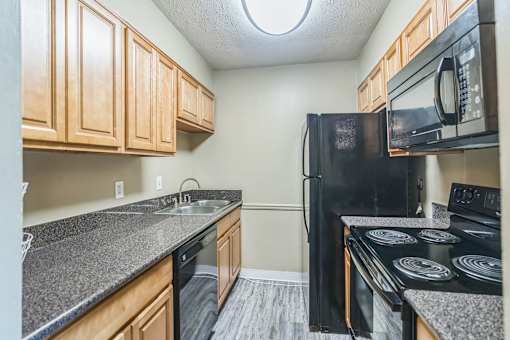 A kitchen with black appliances and wooden cabinets.