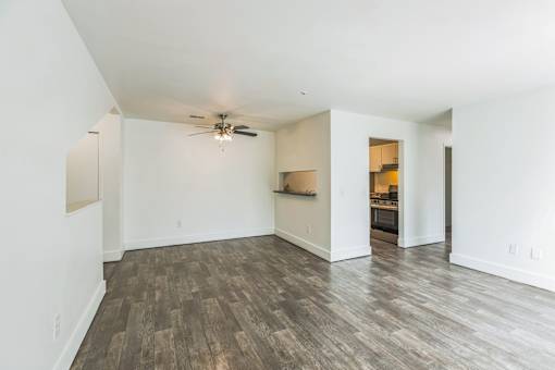 A room with a ceiling fan and wood flooring.