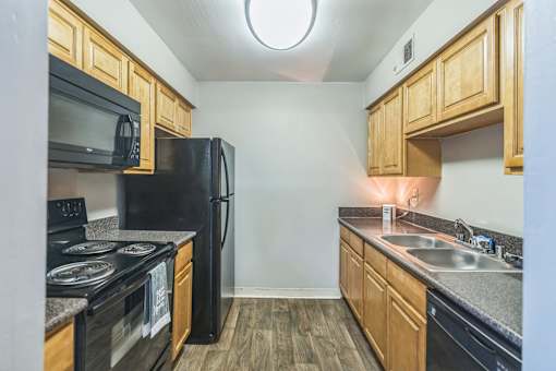 A kitchen with black appliances and wooden cabinets.