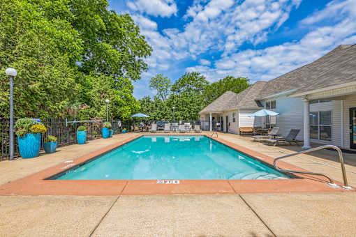 A swimming pool surrounded by trees and a house.