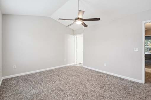 A room with a ceiling fan and carpeted floor.