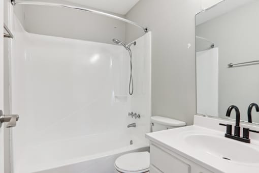 A white bathroom with a toilet, sink, and shower.