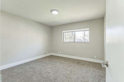 A room with a carpeted floor and a window.