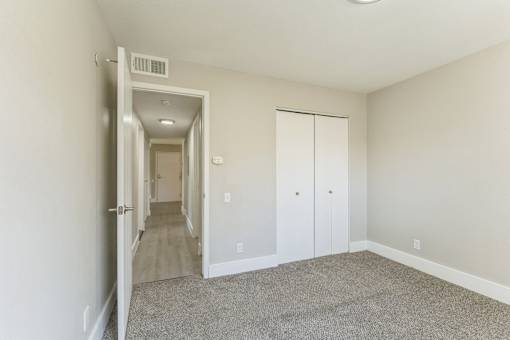 A long hallway with a carpeted floor and white walls.