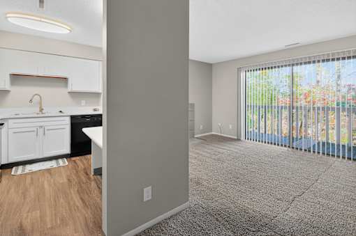 A kitchen with white cabinets and a window with blinds.