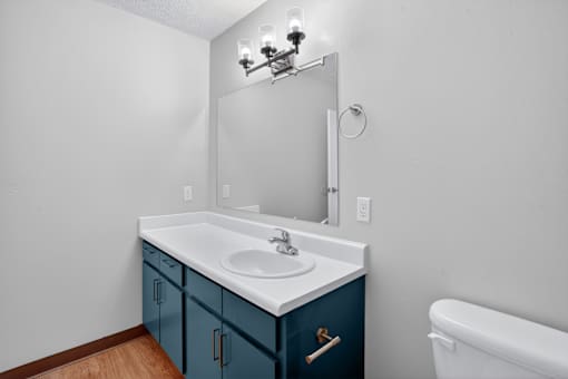A white sink with a blue cabinet and a white bathtub.