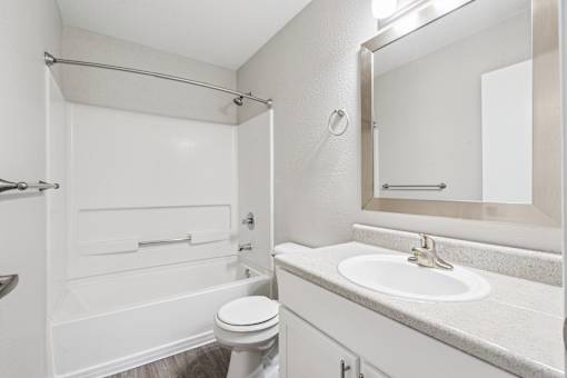 A white bathroom with a toilet, sink, and shower.