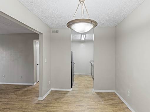 A room with a light hanging from the ceiling and a door on the left.