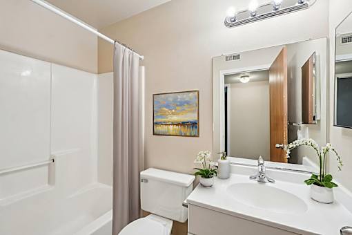 A bathroom with a white toilet, sink, and a painting on the wall.