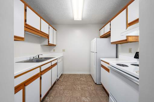 A kitchen with white cabinets and brown trim.