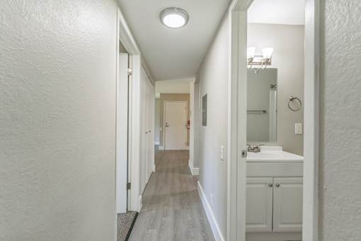 A long hallway with a bathroom at the end.