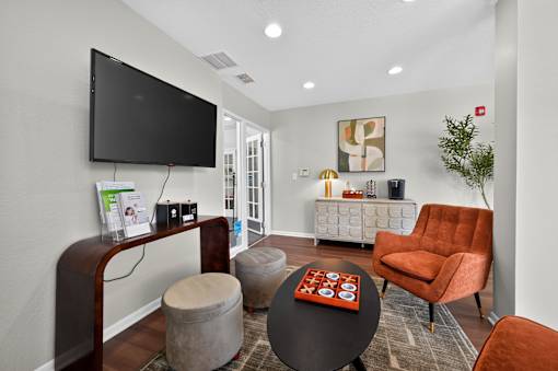 Community room at Renaissance at Carol Stream featuring a television, chair, table, and plant in Carol Stream, IL.