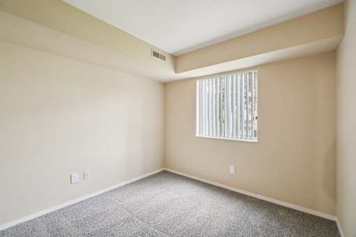 A room with a window covered by a white blind.