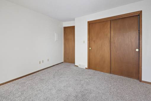 A room with a carpeted floor and two brown doors.