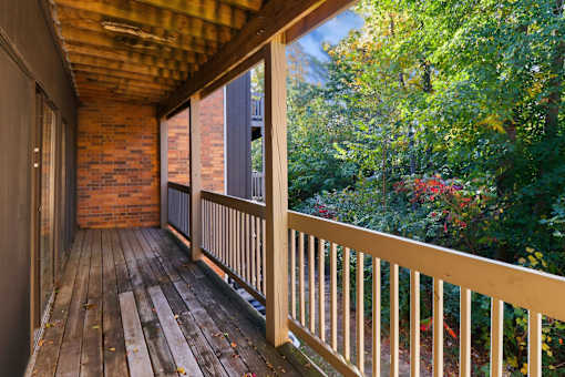 A wooden deck with a railing and a view of a forest.