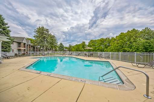 A large swimming pool surrounded by a metal fence and trees.