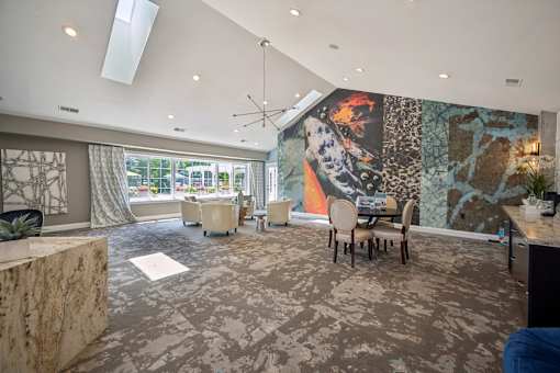A room with a large mural on the wall and a dining table with chairs.