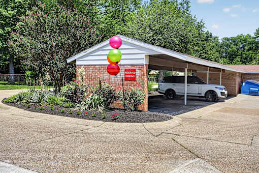 A car is parked in front of a building with a red sign that says "NO PARKING".