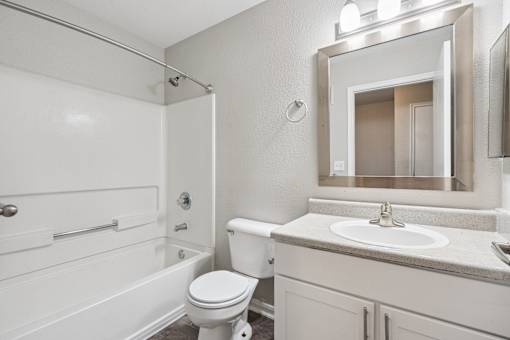 A white bathroom with a toilet, sink, and mirror.