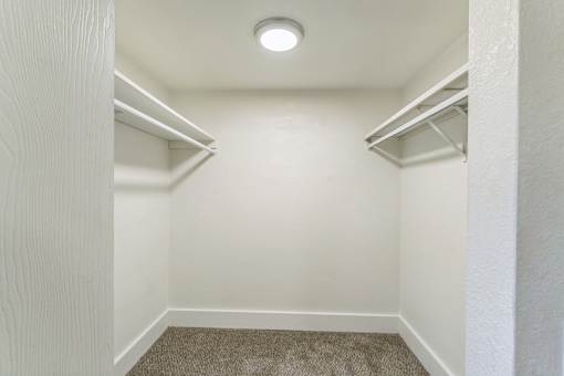 A small, empty room with a carpeted floor and a single light fixture on the ceiling.